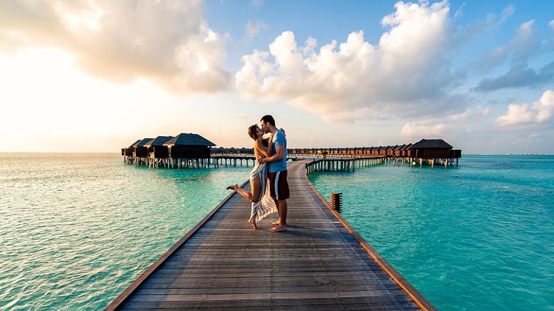 Couple enjoying honeymoon in Bora Bora on a jetty with overwater bungalows in the background