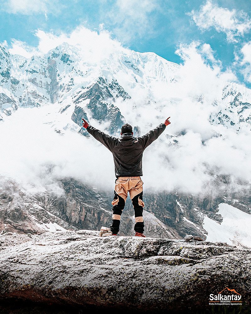 Tourist in the Salkantay pass raising his hands and the bottom of the Salkantay mountain